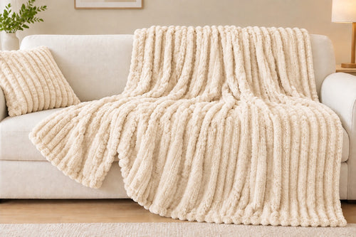 Beige striped faux-fur throw blanket draped on a sofa